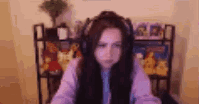 a woman wearing headphones is sitting at a desk in front of a shelf .