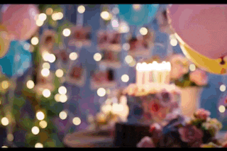 a birthday party with balloons , flowers , a cake , and lights .