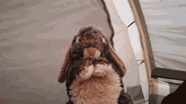 a stuffed animal that looks like a rabbit is standing in front of a tent
