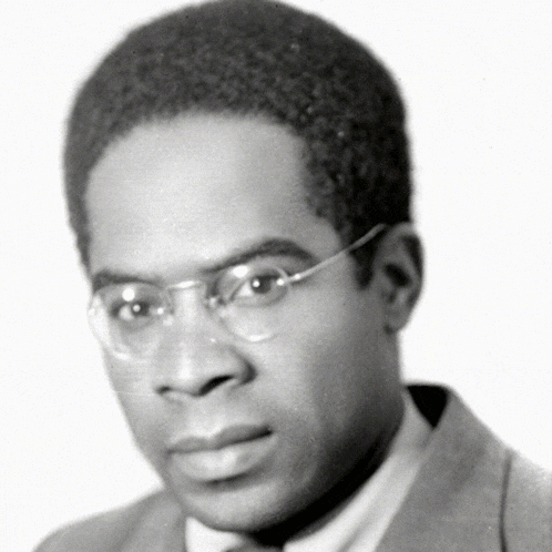 a man with glasses and a suit looks at the camera