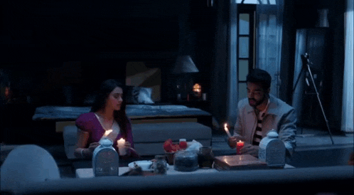 a man and a woman are sitting at a table holding candles .