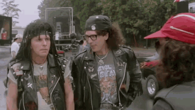 two men in leather jackets and bandanas are standing next to each other .