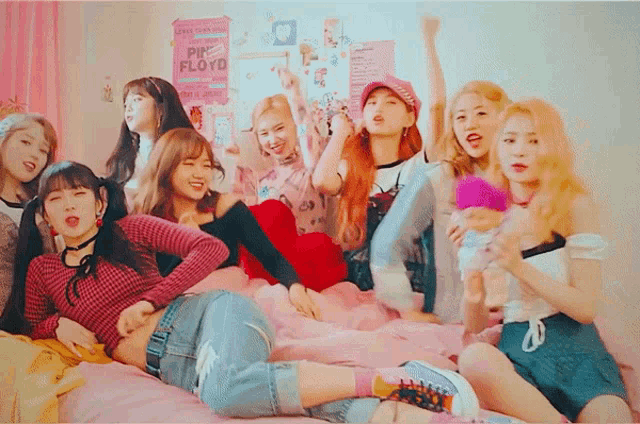 a group of girls sitting on a bed with a pink floyd poster on the wall behind them