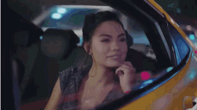 a woman is sitting in a yellow car and smiling