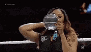 a woman is drinking from a glass in a ring .