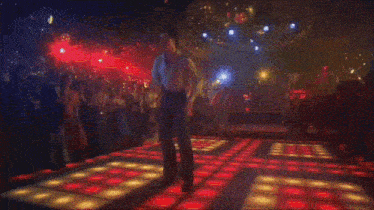 a man is dancing on a disco floor in front of a crowd of people .