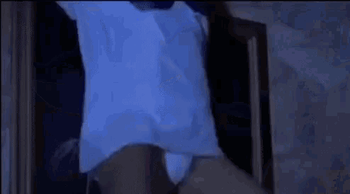a person is standing in a dark room wearing a white shirt and underwear .