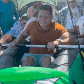 a man in an orange shirt is smiling while sitting in a green raft