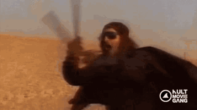 a woman is standing in the middle of a desert wearing sunglasses and a mask .