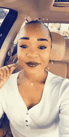 a woman is sitting in the back seat of a car taking a selfie with her phone .