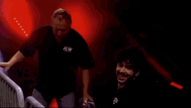 a man is laying on the ground in a boxing ring while a man stands behind him .