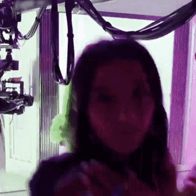 a woman is taking a picture of herself in front of a camera in a purple room .