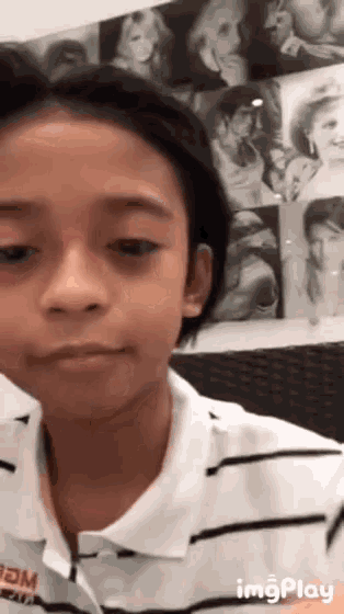 a young boy wearing a striped shirt that says imgplay on it