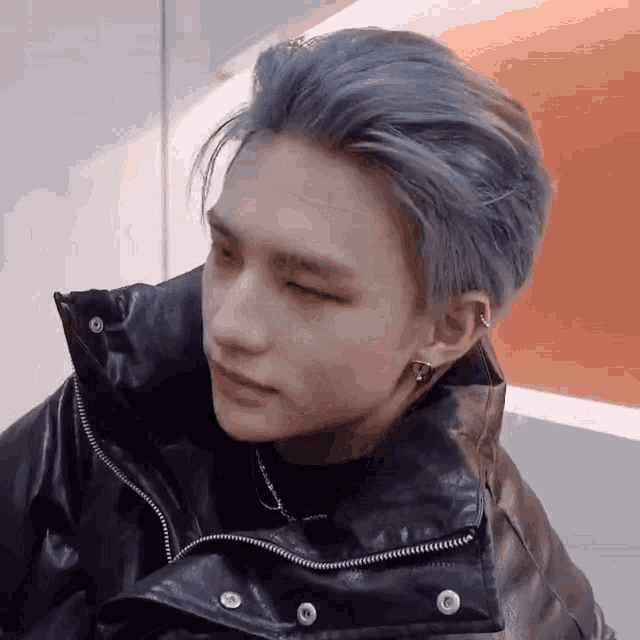 a close up of a person with blue hair wearing a black jacket .