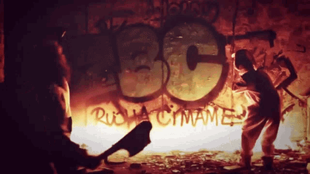 a man is holding an axe in front of a wall with graffiti on it