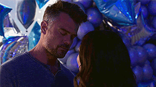 a man and a woman are standing next to each other in front of balloons .