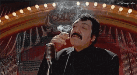 a man with a mustache smoking a cigarette in front of a microphone