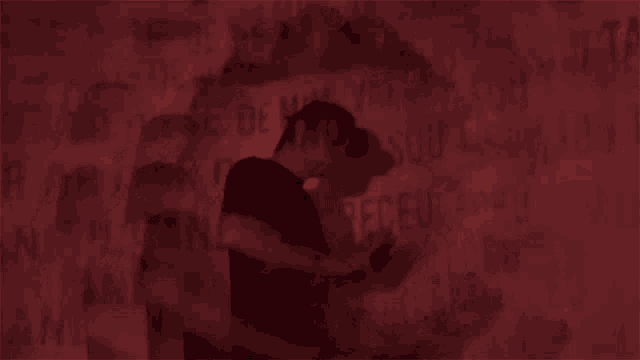 a man is standing in front of a wall that has a lot of writing on it