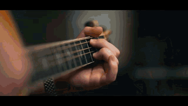 a person is playing an acoustic guitar with a watch on their wrist