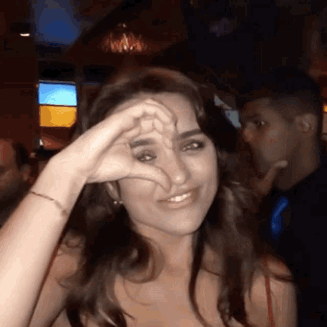 a woman is making a heart shape with her hand