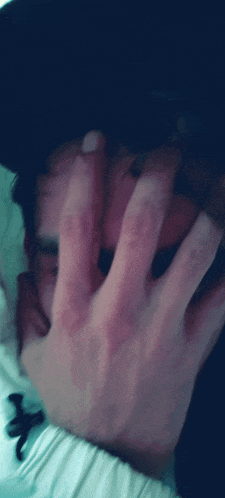 a close up of a person covering their face with their hand in a blurry photo
