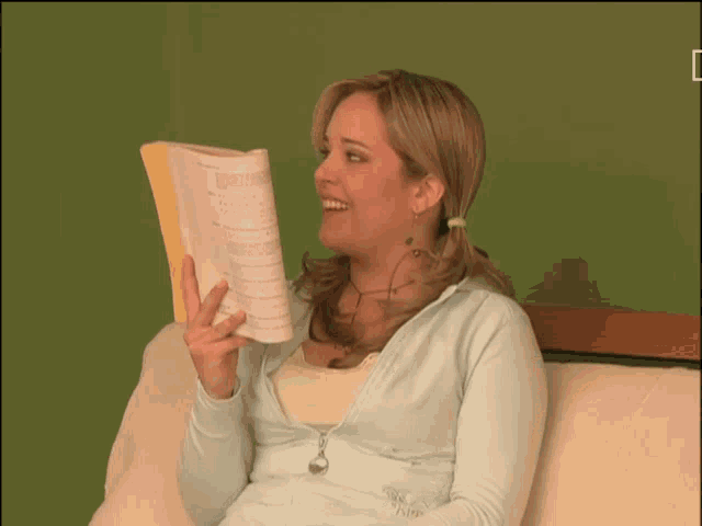 a woman sits on a couch holding a piece of paper that says ' a ' on it