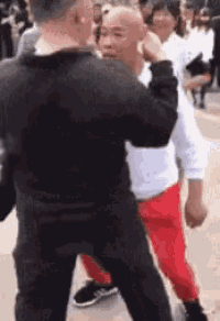 a man in a black shirt and red pants is standing next to another man in a black shirt and red pants .