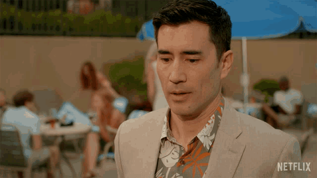 a man in a suit and hawaiian shirt is standing in front of a netflix logo