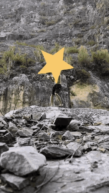 a person is doing a handstand on a rocky hillside with a yellow star covering their face