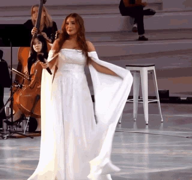 a woman in a white dress stands on a stage