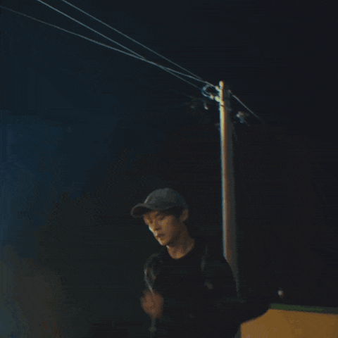 a man wearing a baseball cap is running in a dark room