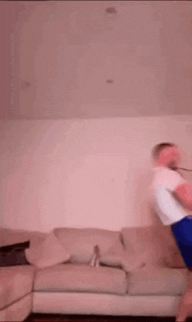 a man is jumping in the air in front of a couch .