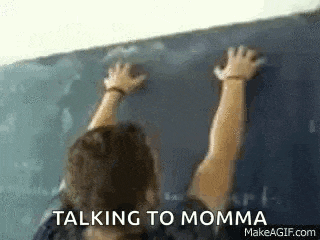a woman is standing in front of a blackboard with her hands on it and talking to momma .