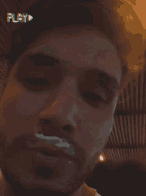 a man with a beard is smoking a cigarette with a play button above his head