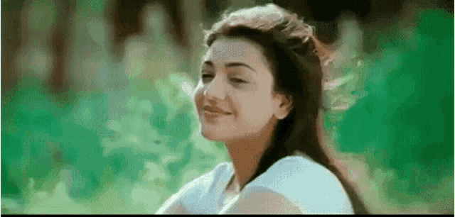 a woman in a white shirt is smiling in a park .