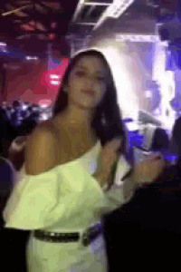 a woman in a white dress is dancing in a crowded room
