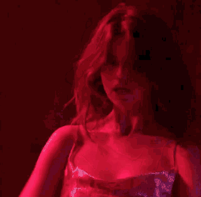 a woman in a red dress is making a funny face in a red light .