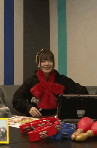 a woman wearing a red scarf is sitting on a couch next to a table with tambourines .