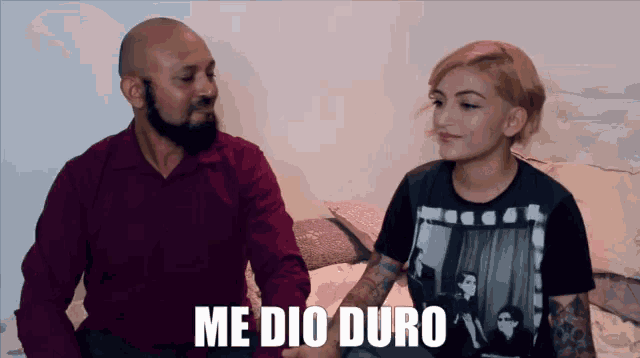 a man and a woman sitting on a bed with medio duro written on the bottom