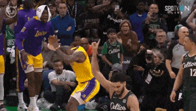 a basketball player is jumping in the air in front of a crowd .