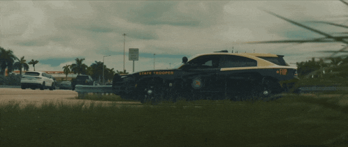 a state trooper car is parked in the grass