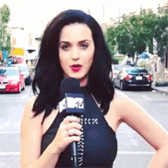 a woman in a black top is holding a microphone with the letter m on it