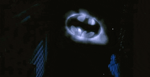 the batman logo is glowing in the dark and flying through the air .