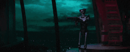 a robot is standing in a dark room with a blue light behind it .