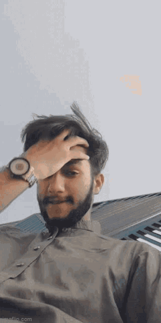 a man with a beard wearing a watch covering his face