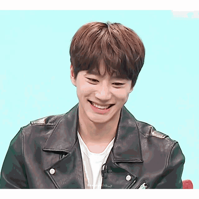 a young man wearing a black leather jacket and a white shirt is smiling