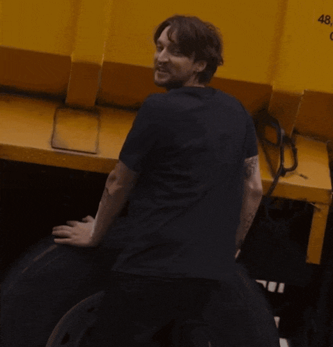 a man in a black shirt stands next to a yellow dumpster with the number 48 on it