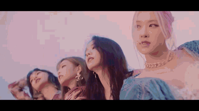 a group of young women are standing next to each other looking up at the sky .