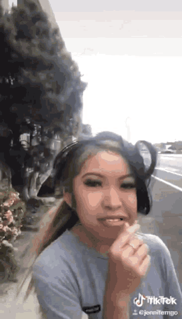 a girl wearing a hat and a blue shirt is standing on the sidewalk .