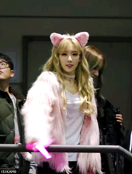 a woman wearing a pink fur coat and a pink cat ears headband